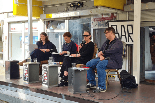 Susanne Hinneberg auf einem Podium mit Katja Kipping und Andrej Holm, moderiert von Isette Schuhmacher (ganz links)