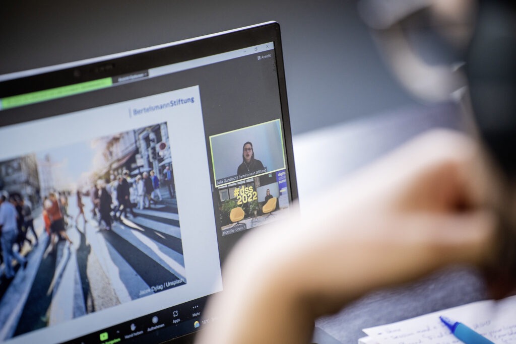 Eine Person sitzt vor einem aufgeklappten Laptop.
